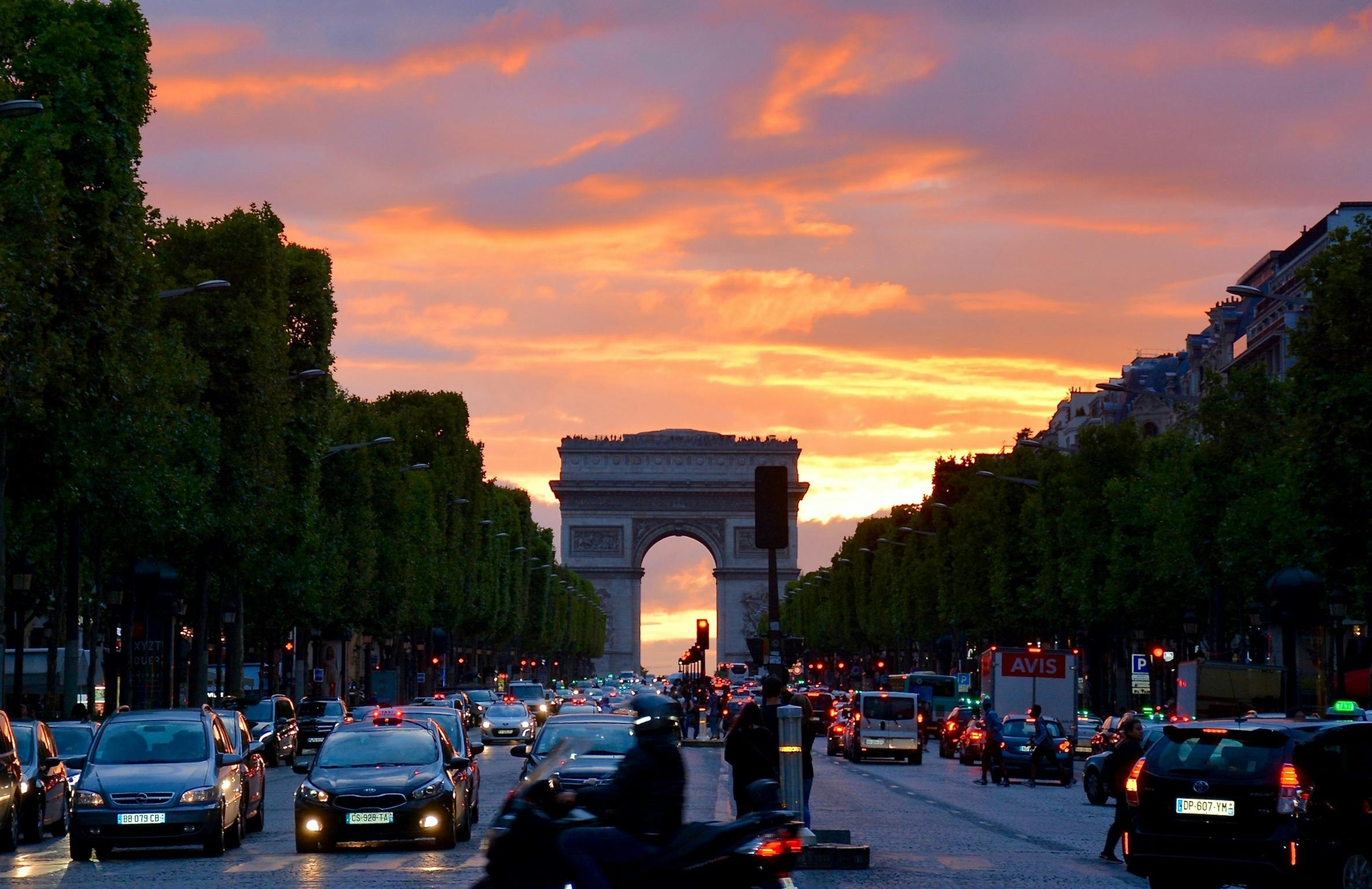 Vivid sunset sky over Arc de Triomphe, capturing Parisian traffic and architecture. location food truck