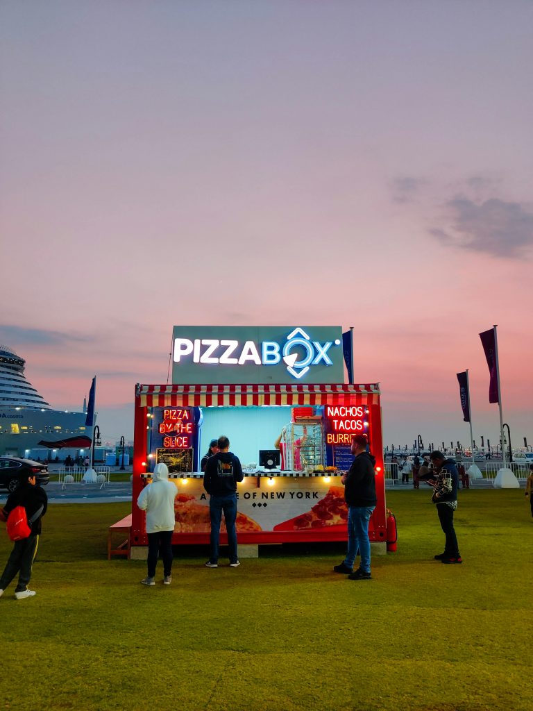 Pizzabox food stall attracting customers during sunset in Doha, Qatar.