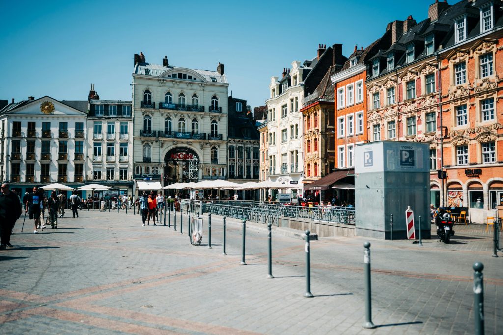 Vibrant street view in Place Du General-De-Gaulle, Lille, France showcasing colorful townhouses and lively pedestrian activity.
