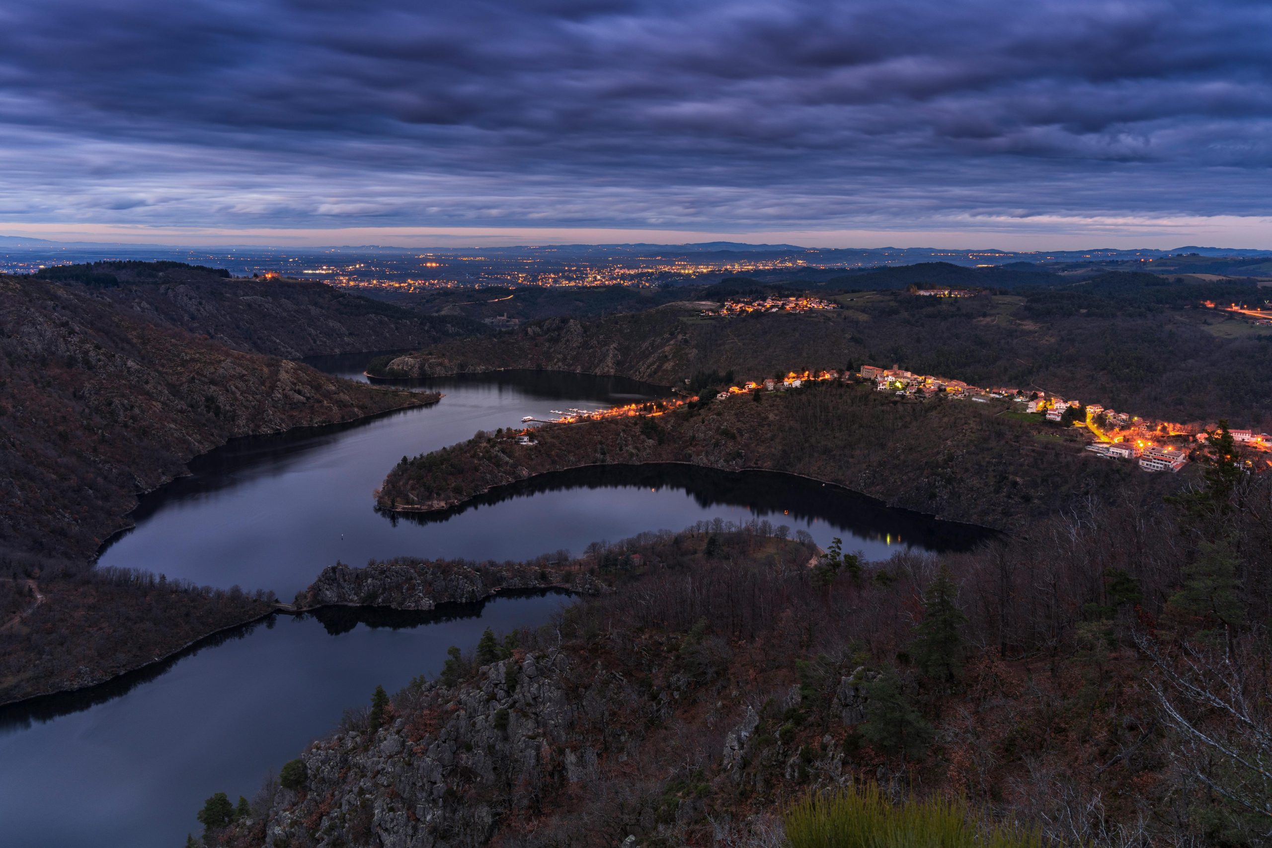 Twilight view overlooking the winding river and illuminated landscape of Saint-Étienne, France.