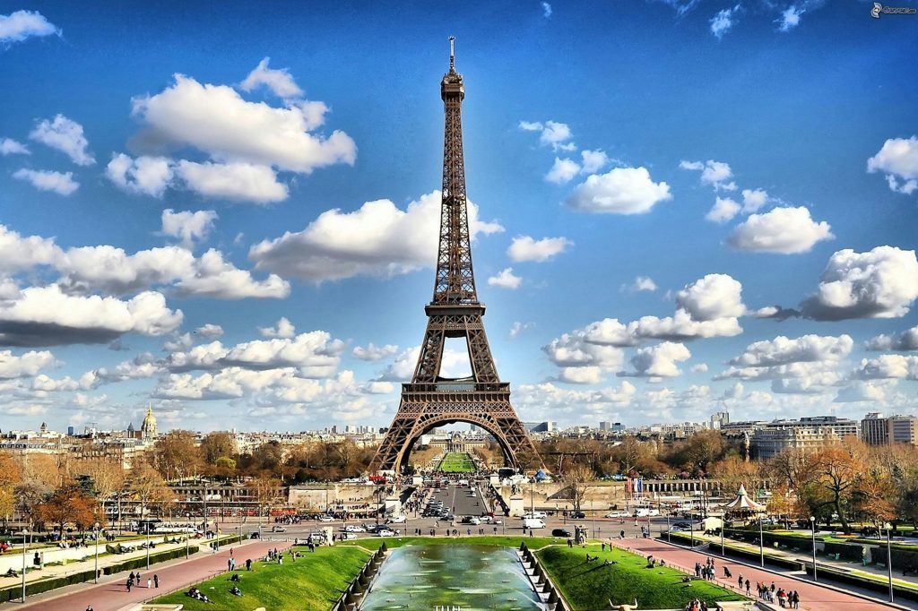 Location Food truck Paris Stunning view of the Eiffel Tower with a backdrop of fluffy clouds and blue sky in Paris.