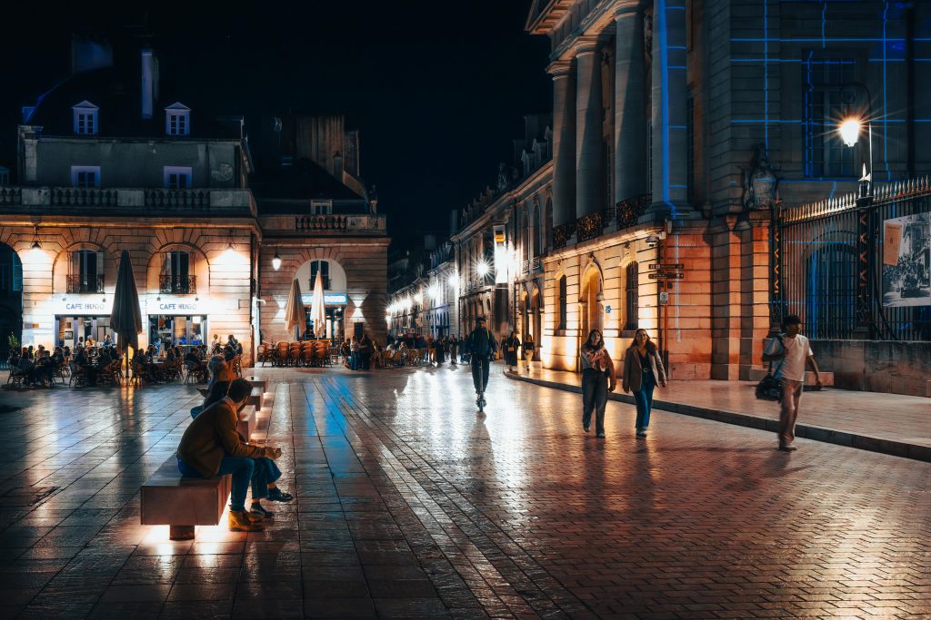 Explore the vibrant nightlife of Dijon, France with illuminated architecture and lively streets.
